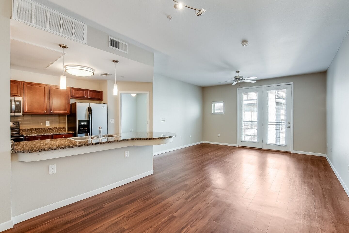 an empty living room with a kitchen and a large window