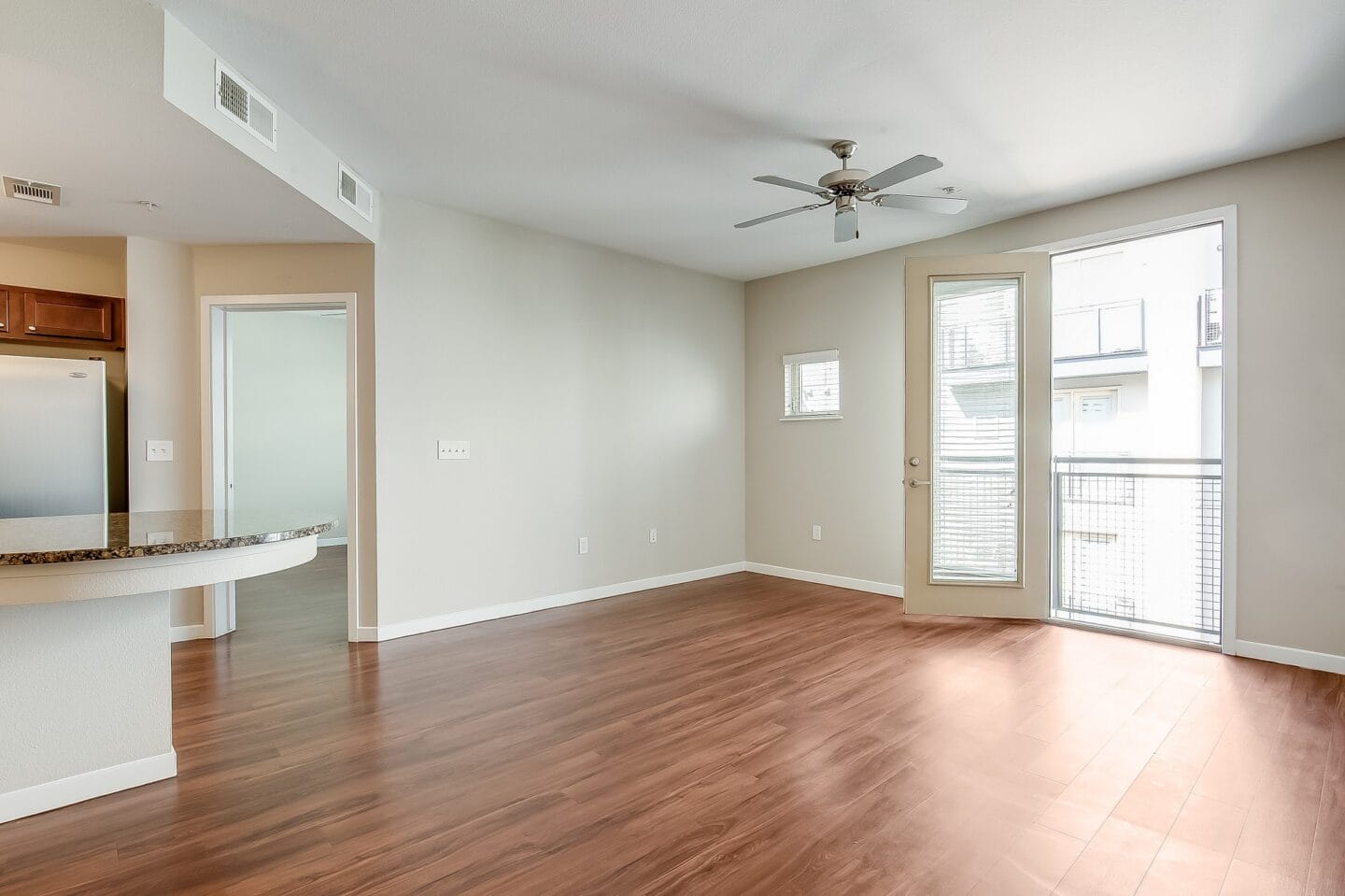 an empty living room with wood floors and a ceiling fan