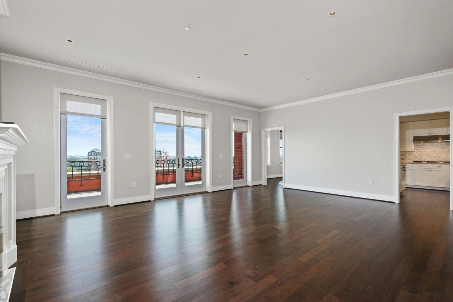 an empty living room with hard wood floors and a balcony