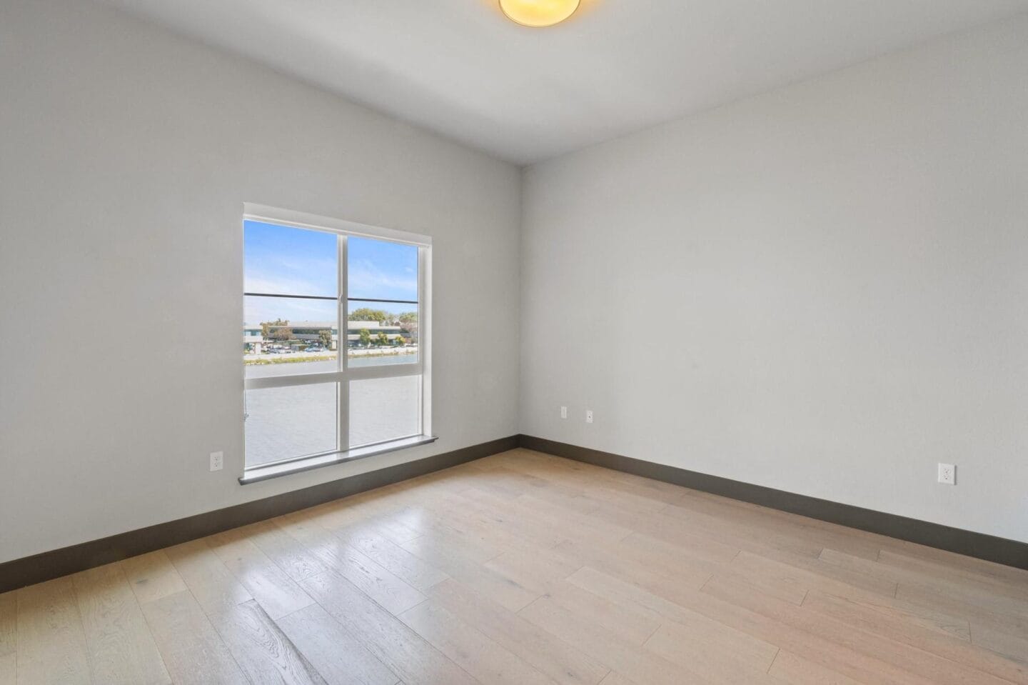 a bedroom with a large window and hardwood floors