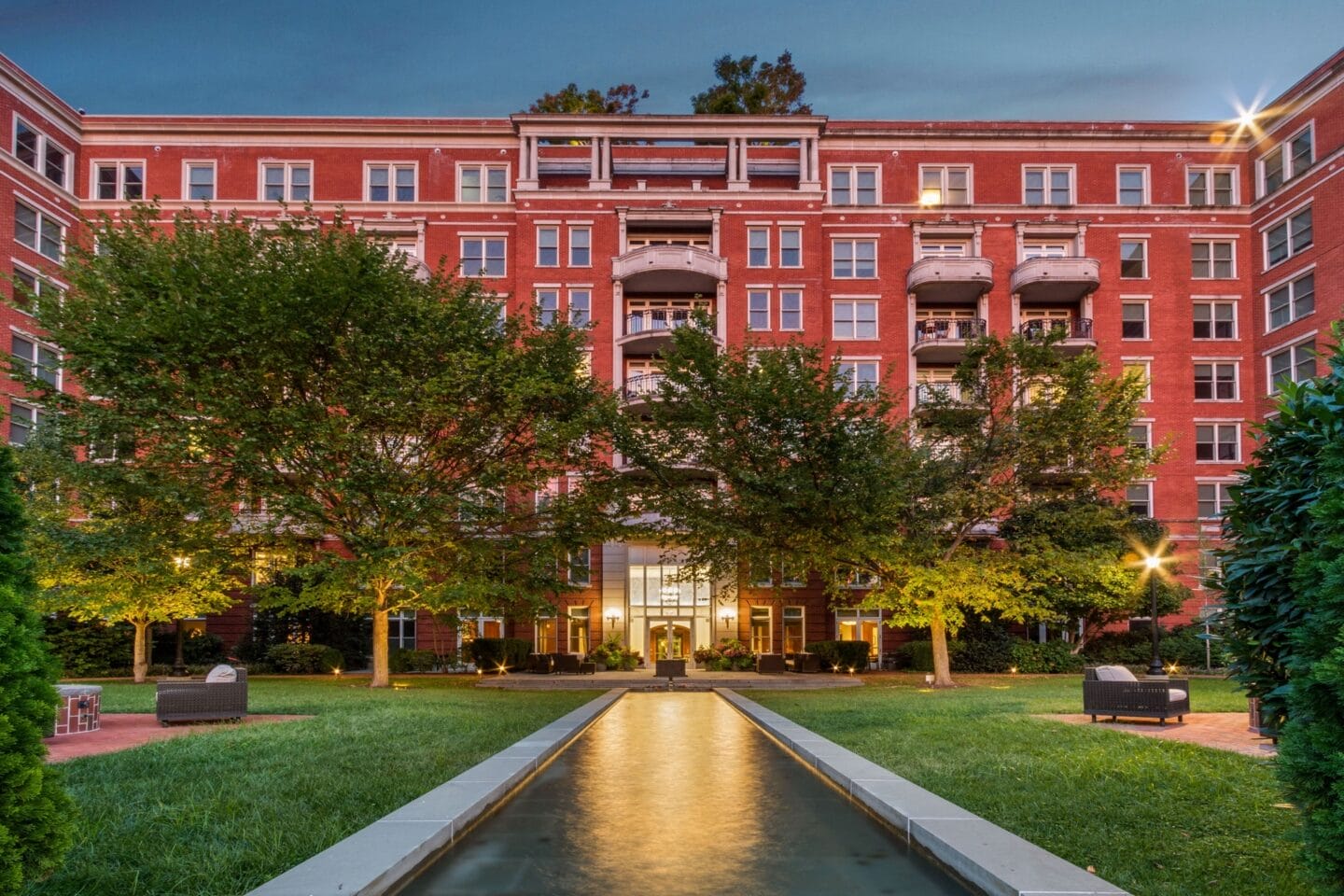 a courtyard with a fountain in front of a large red building