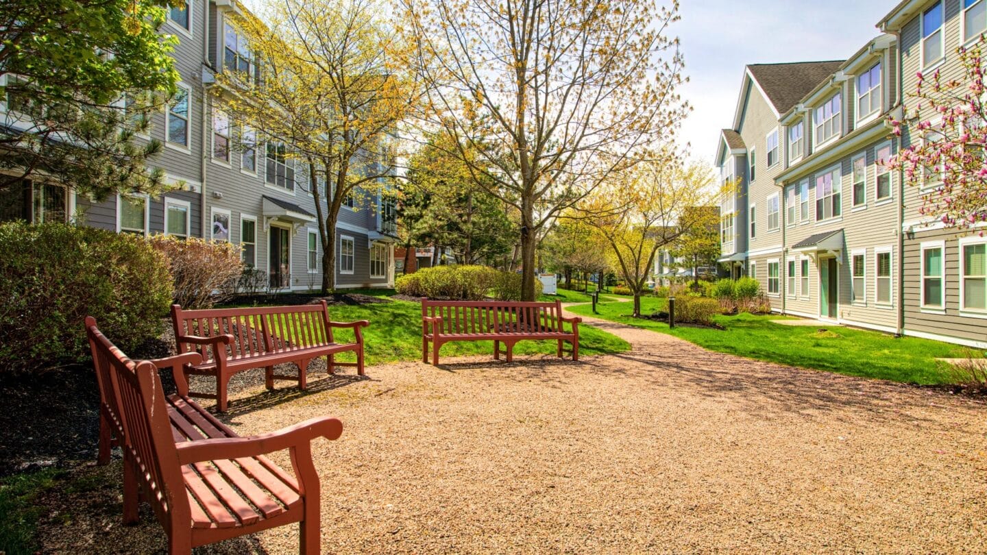 a courtyard with benches and trees in front of the exterior of building