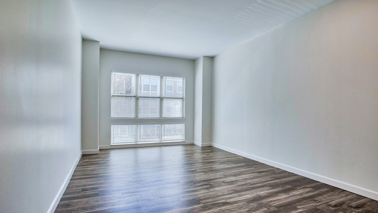 a bedroom with hardwood flooring and a large window