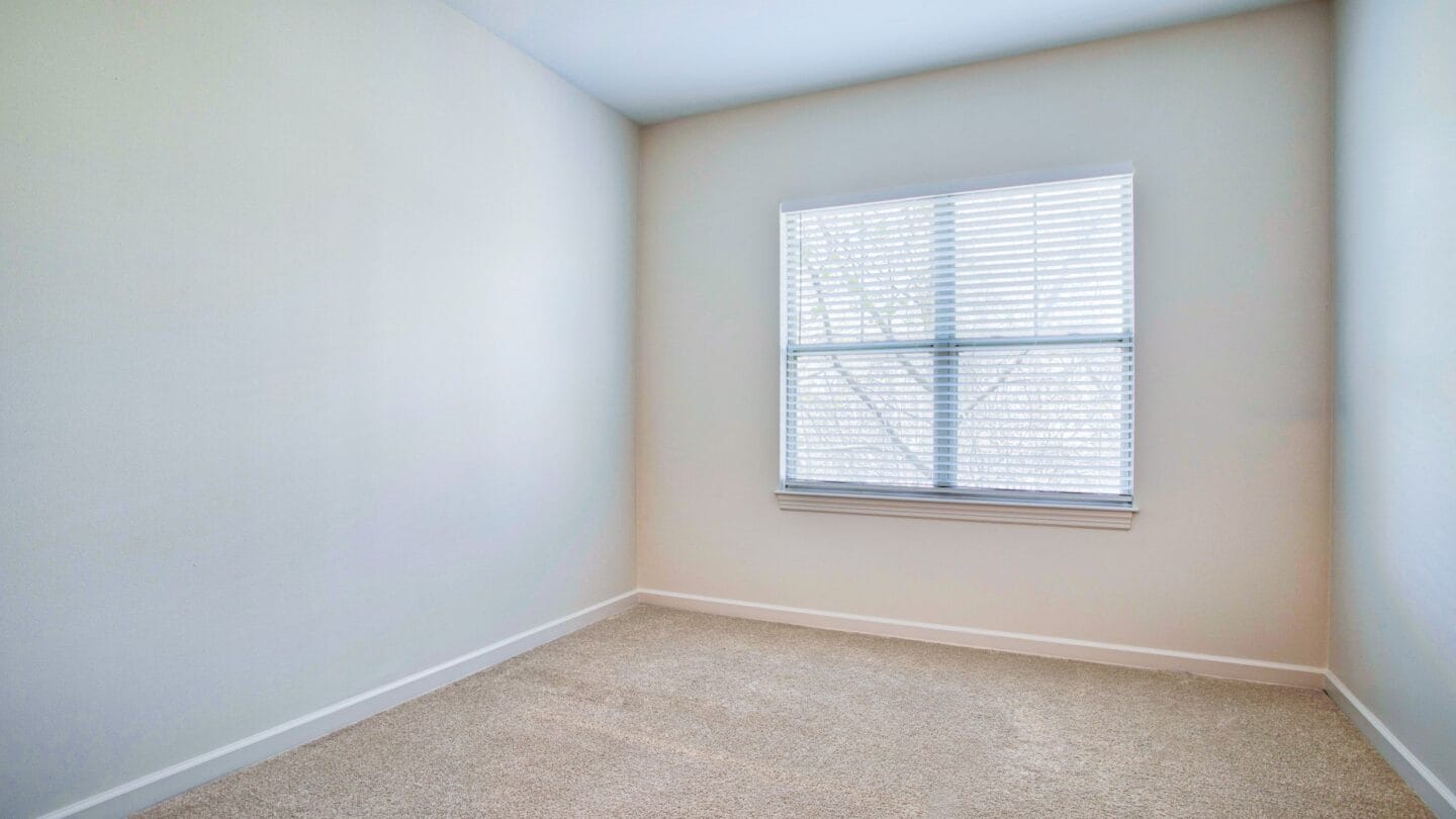 a bedroom with white walls and a window