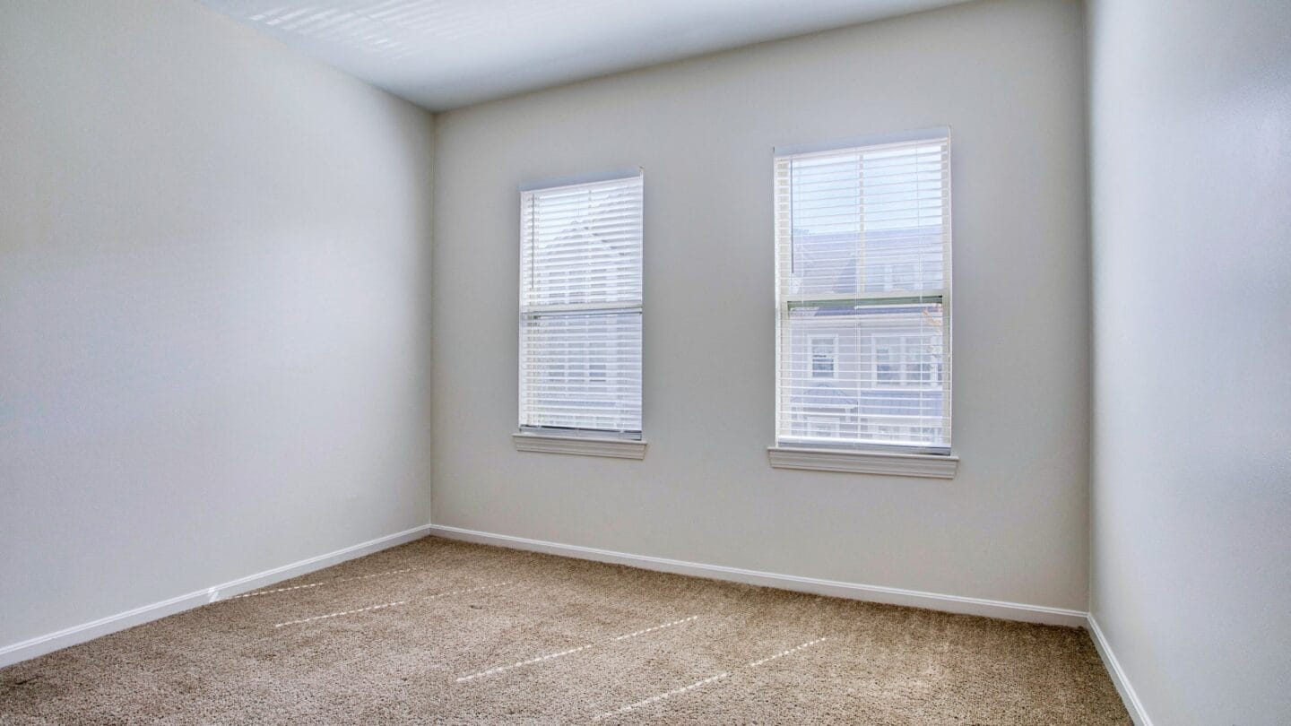 a bedroom with two windows and a carpeted floor