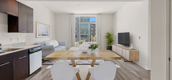 A modern living room featuring a stylish sofa, a coffee table, and decorative accents, with large windows allowing natural light to fill the space