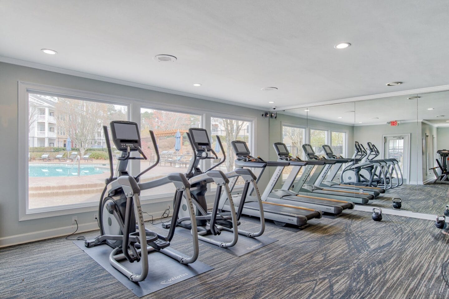 a row of treadmills and exercise machines in a fitness room