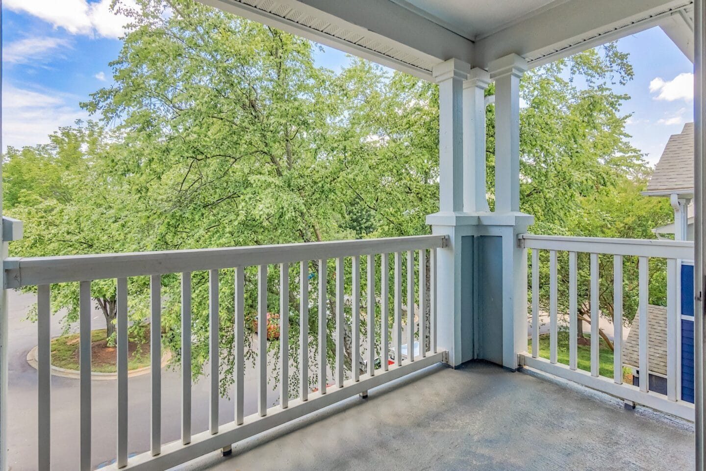 A balcony with a white railing and a tree in the background