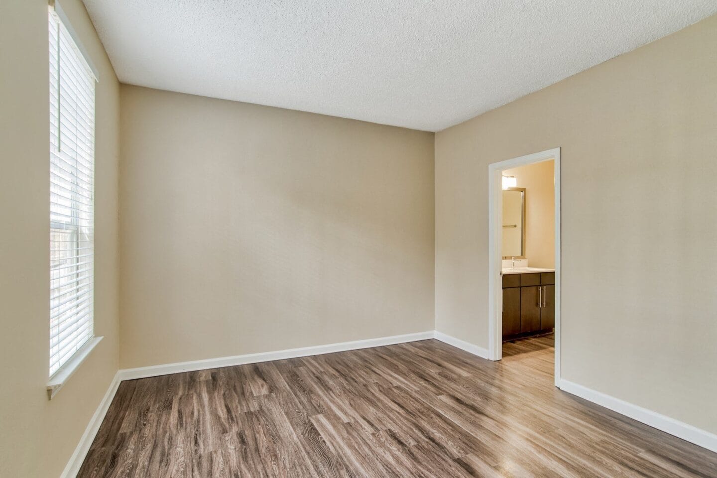 an empty room with a bathroom in the background