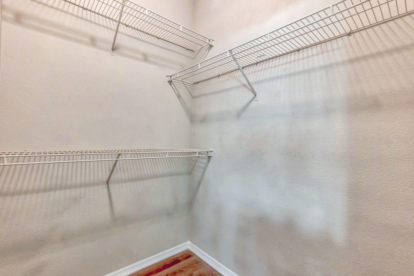 A walk in closet in a bedroom with white walls and metal shelves