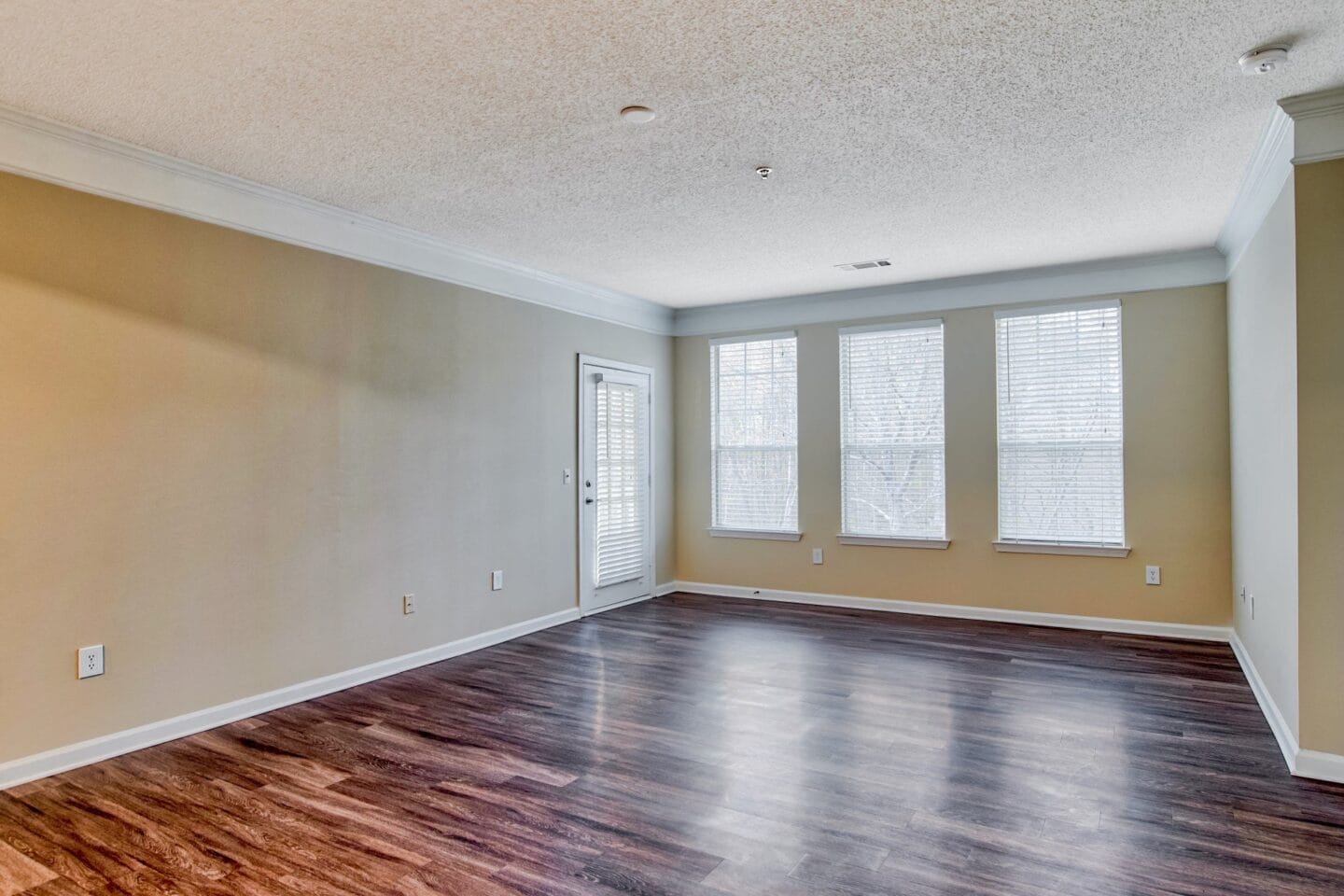 a bedroom with hardwood floors and three windows