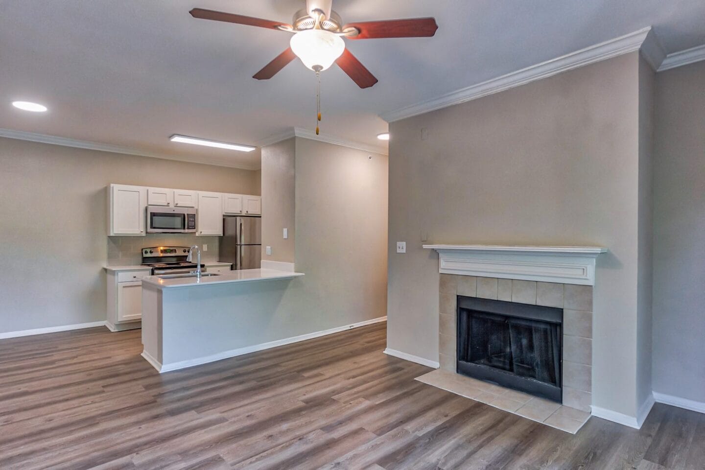 A living room with a fireplace and a kitchen in the background at Windsor Addison Park, Charolette, NC