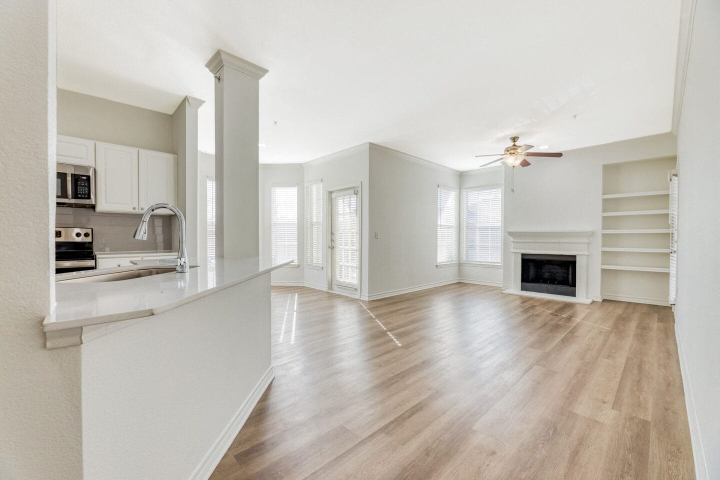 Kitchen and living room with hardwood floors and a fireplace at Windsor Westbridge, Carrollton, TX