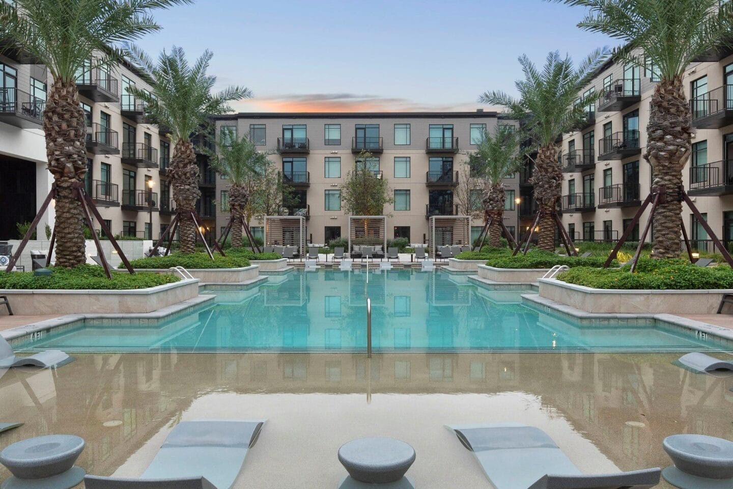 a swimming pool with palm trees in front of an apartment building at The Sterling at Regent Square, Texas, 77019