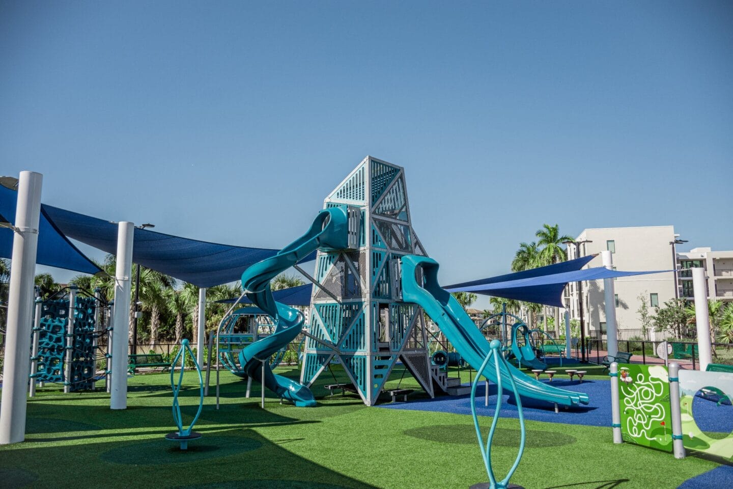 a playground with two slides and a trampoline on a sunny day