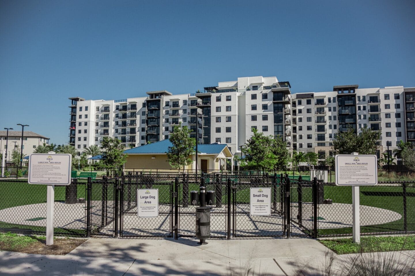 a park with a fence and signs in front of an apartment complex