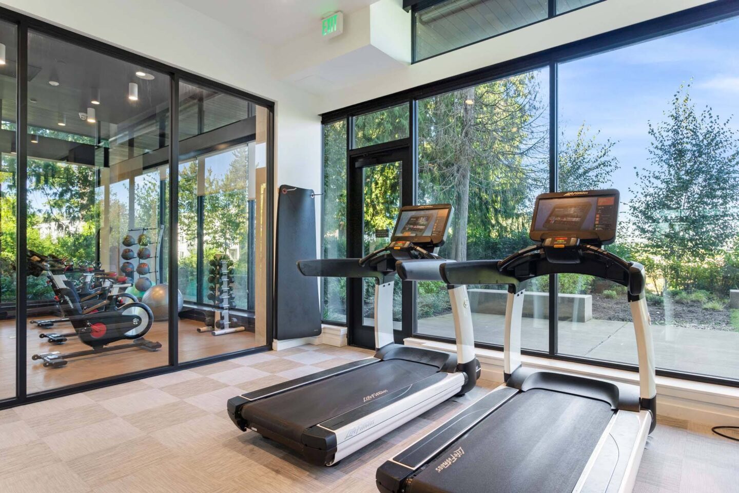 Two treadmills in a gym with a view of trees outside the window at Windsor Totem Lake, 11723 NE 117th Ct, Kirkland, WA 98034.