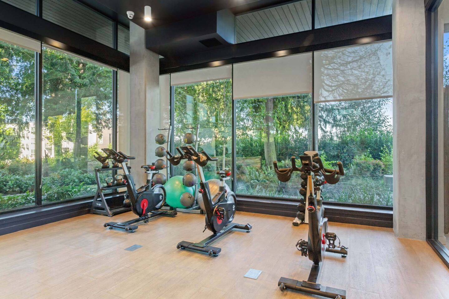 A gym with exercise bikes and a view of trees outside at Windsor Totem Lake, 11723 NE 117th Ct, Kirkland, WA 98034.