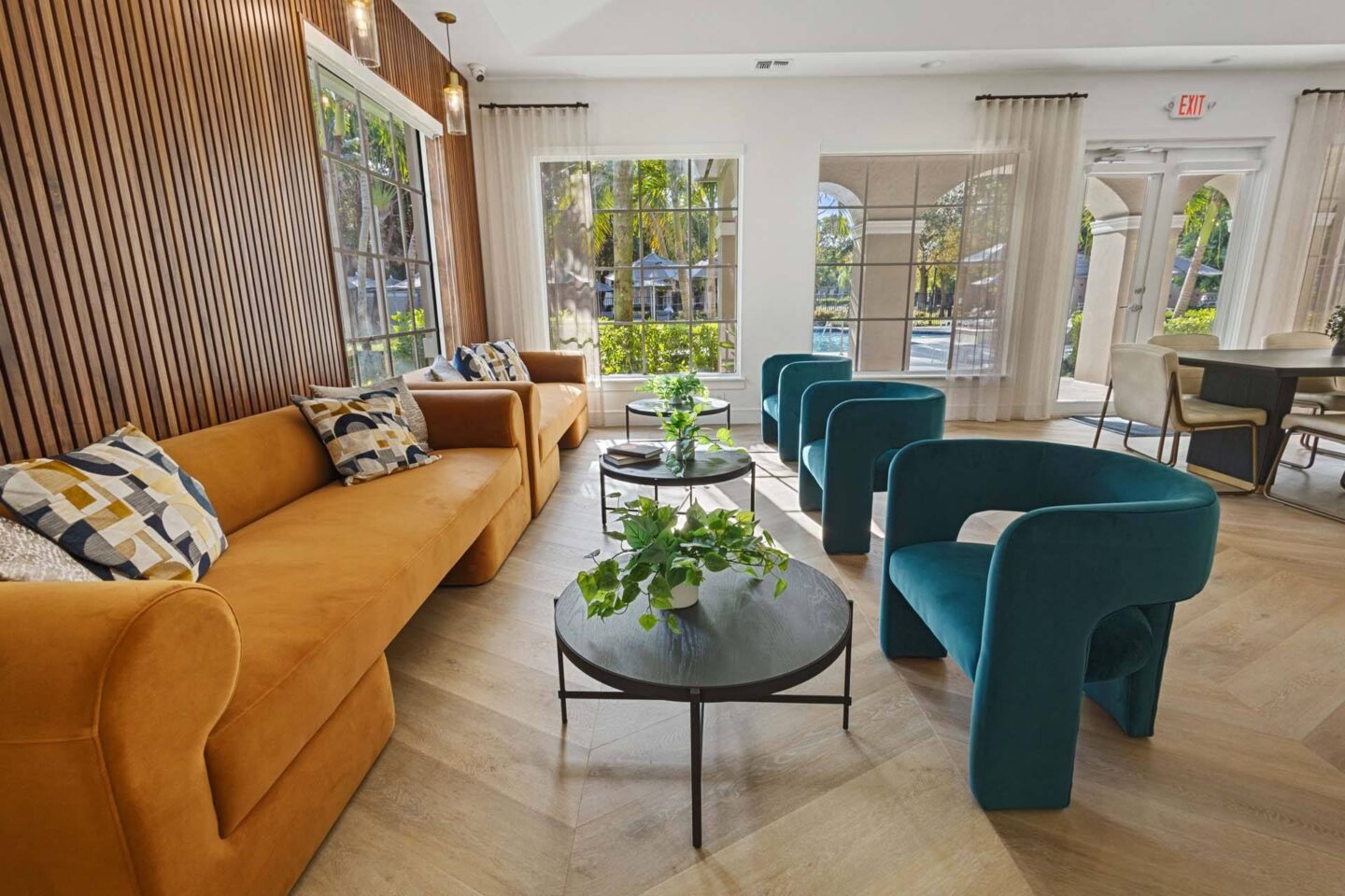 A living room with a yellow couch, a green chair, and a coffee table with a plant on it.