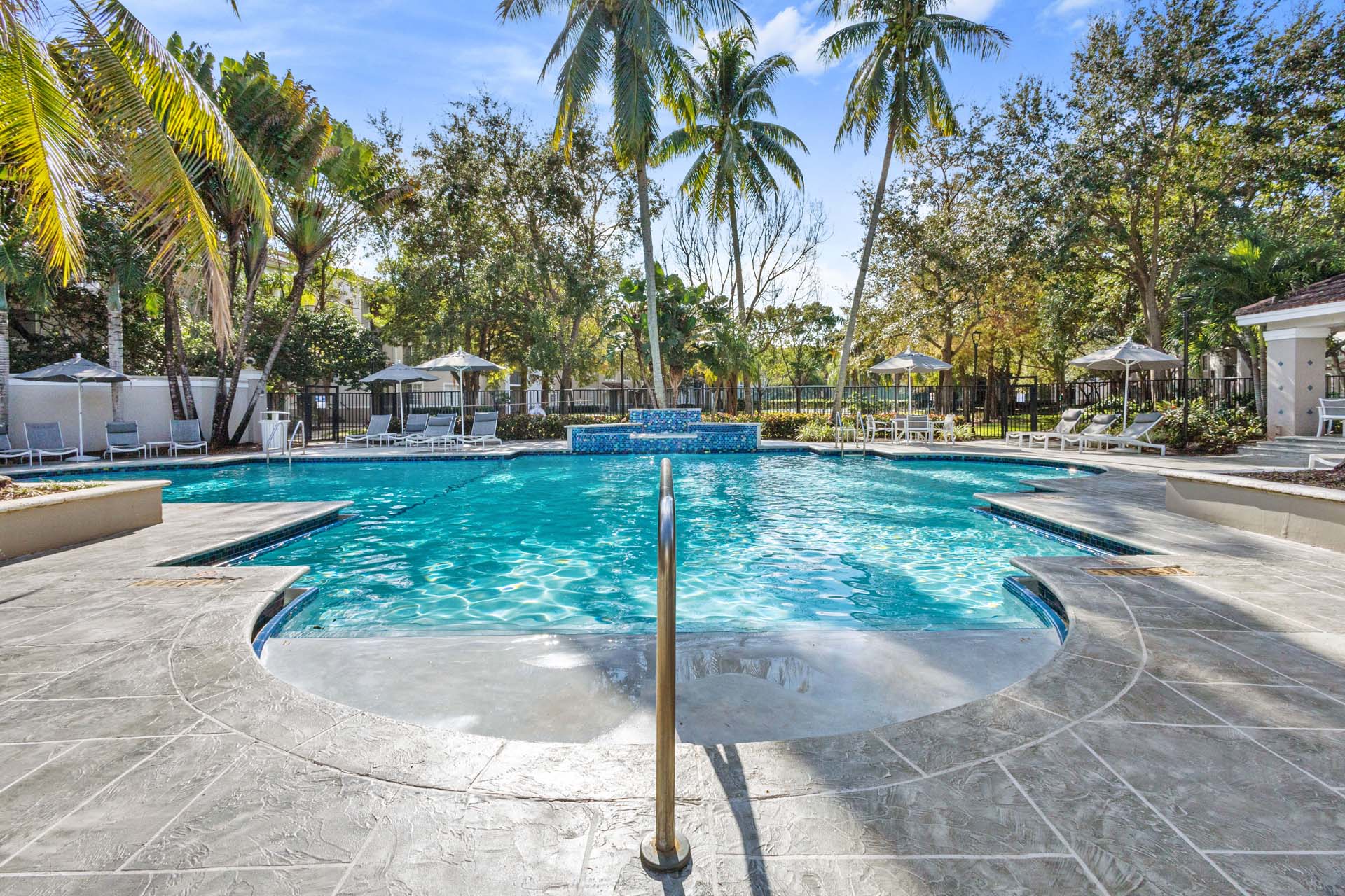 A large outdoor swimming pool surrounded by palm trees at Windsor Coconut Creek, Coconut Creek, 33073.