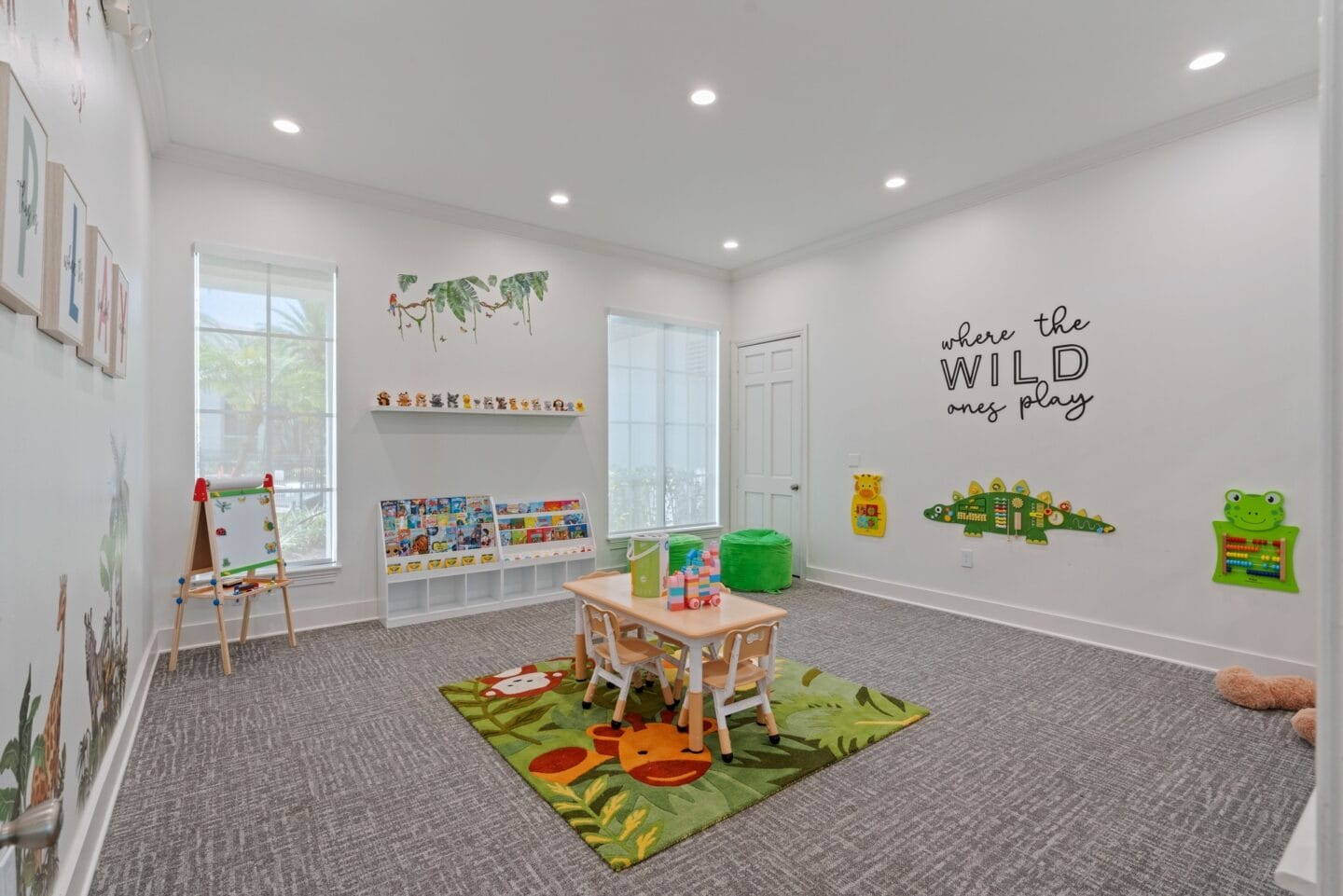 a play room with a table and chairs and a wall with a sign that reads