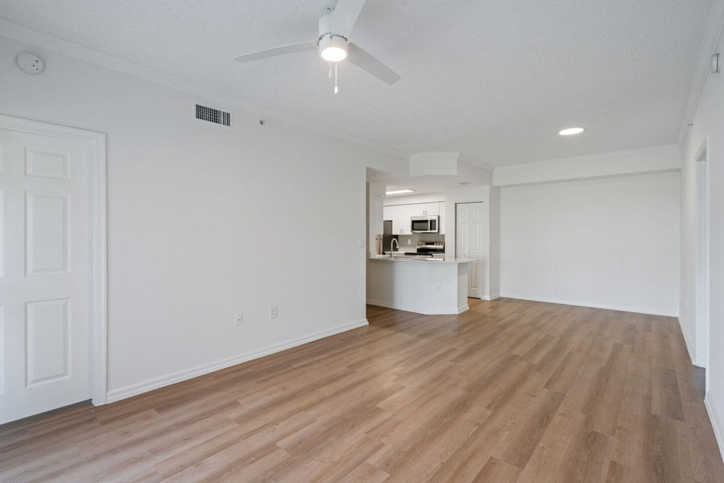 an empty living room with white walls and a ceiling fan