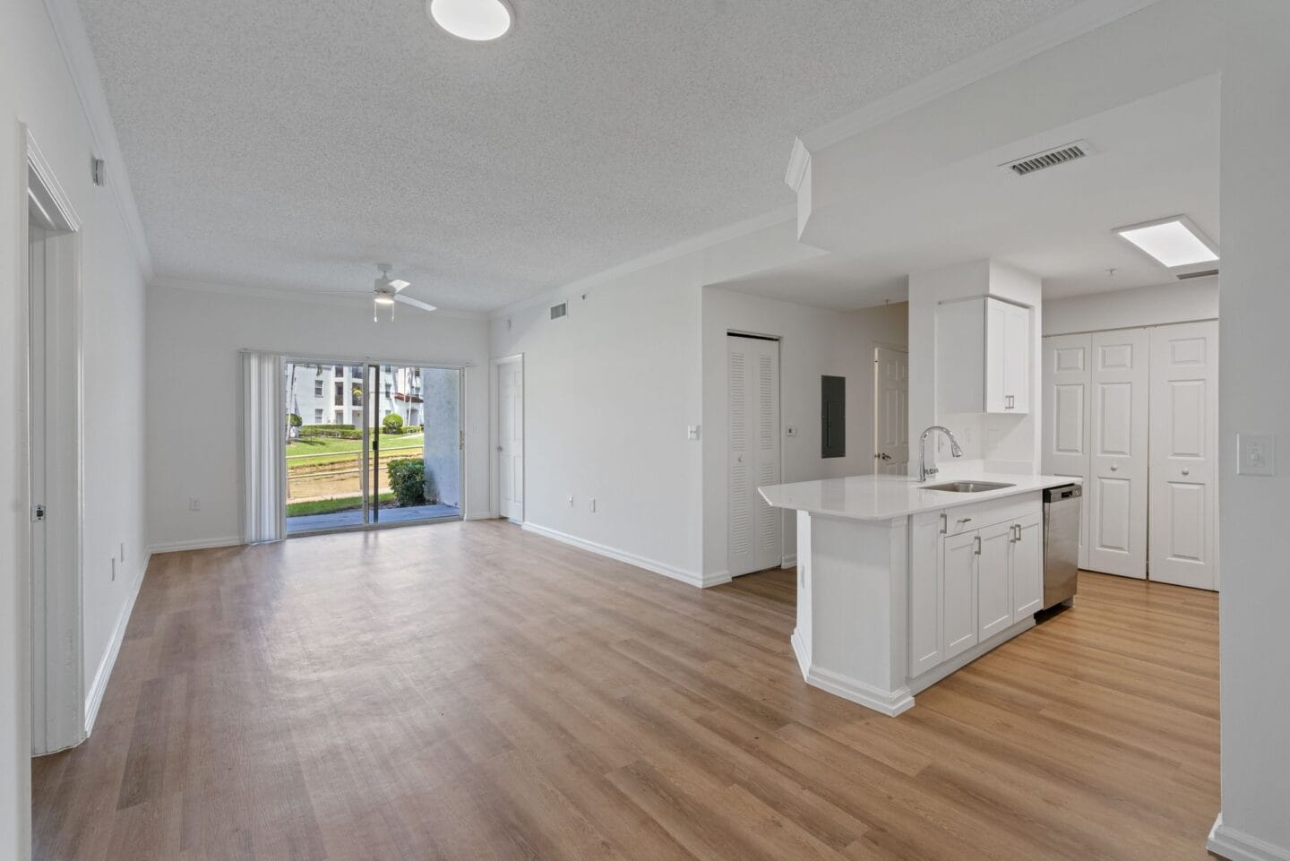 an open living room and kitchen with white cabinets and wood flooring