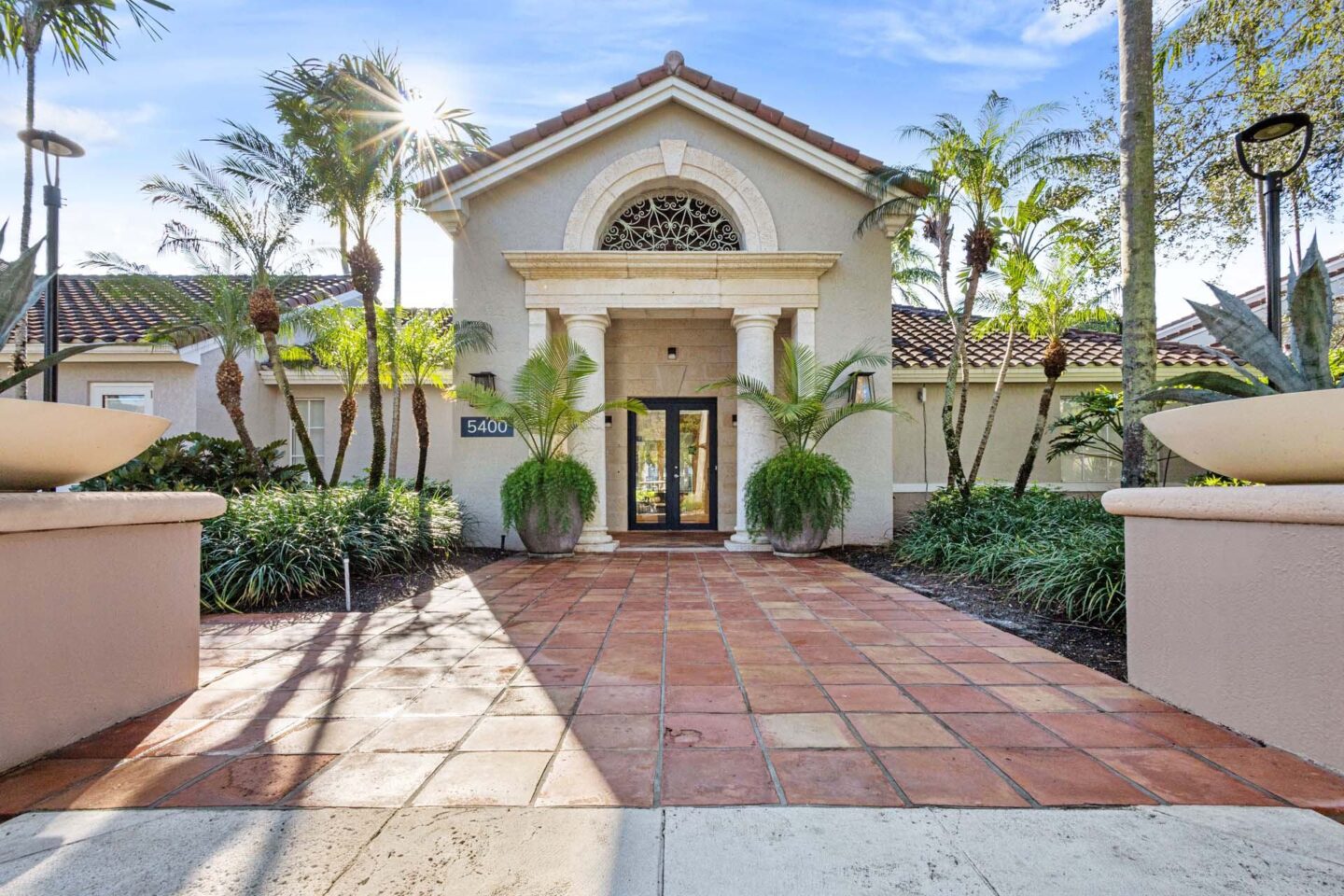 A building exterior with a tiled walkway leading to the front door at Windsor Coconut Creek, Coconut Creek, 33073.