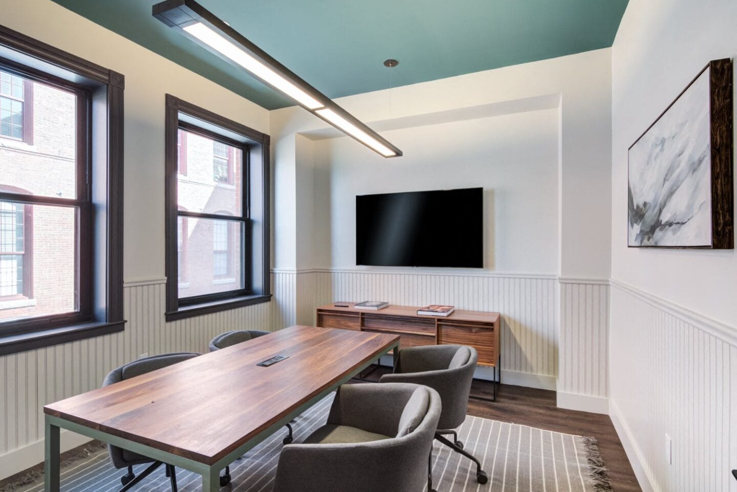 a conference room with a wooden table and chairs and a flat screen tv on the wall