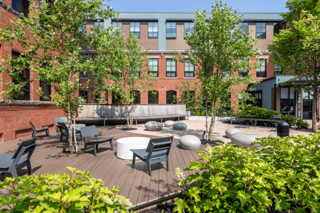 A courtyard with trees benches and a fire pit at Windsor Radio Factory, Melrose, MA