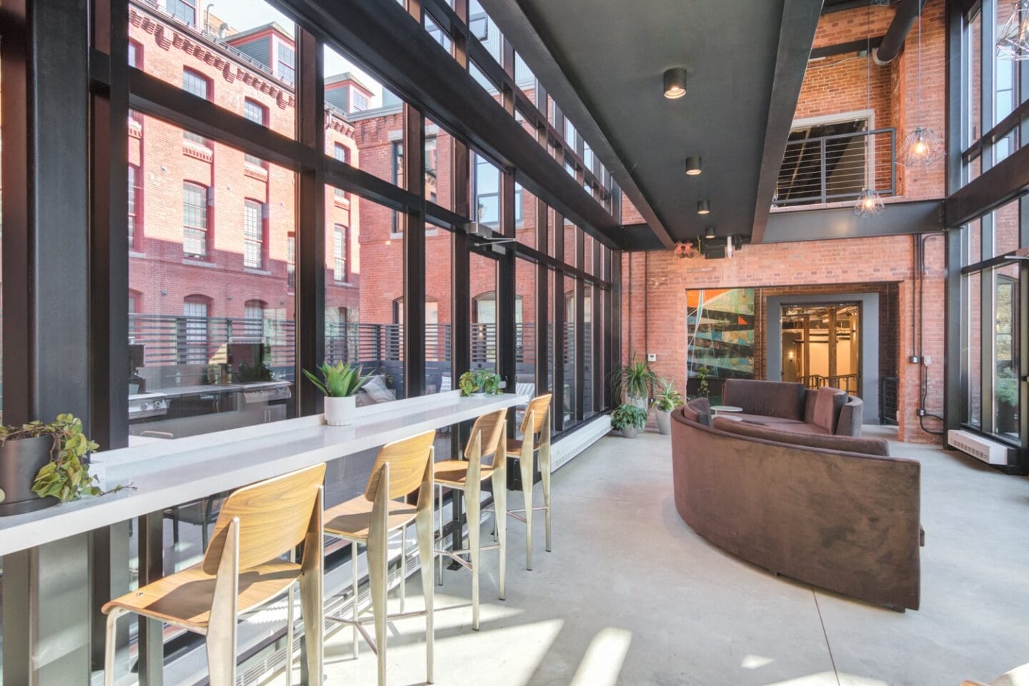 a large open space with a long white bar with wooden chairs and a red brick building in