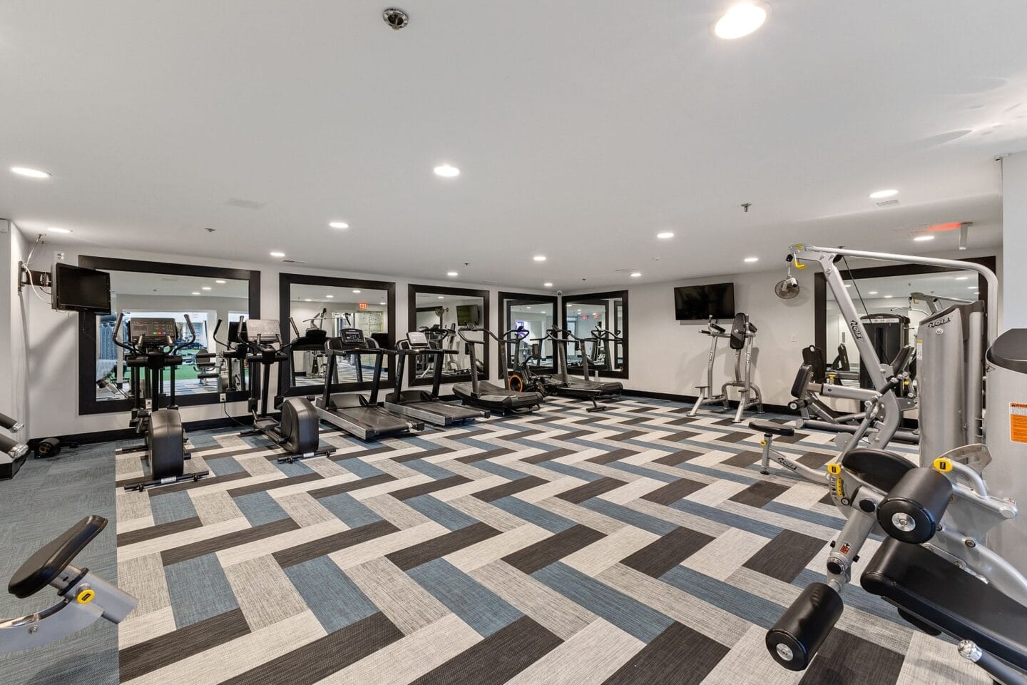 a gym with cardio machines and weights on a checkered floor