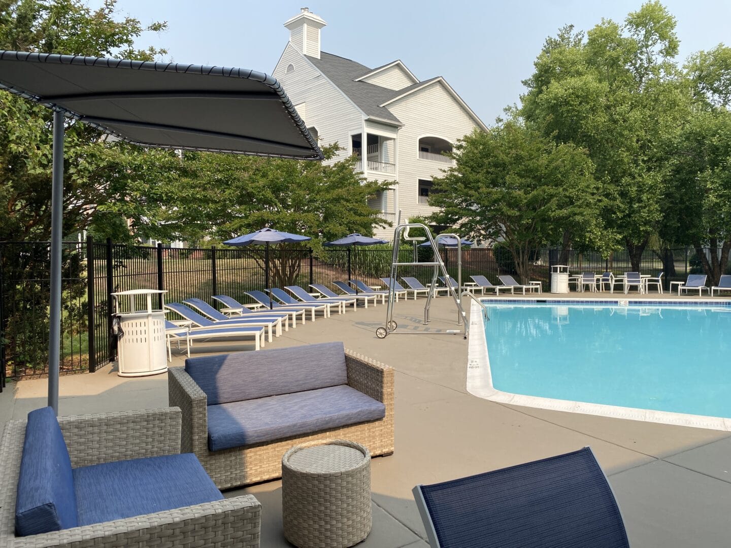 a pool with chairs and umbrellas and a house in the background