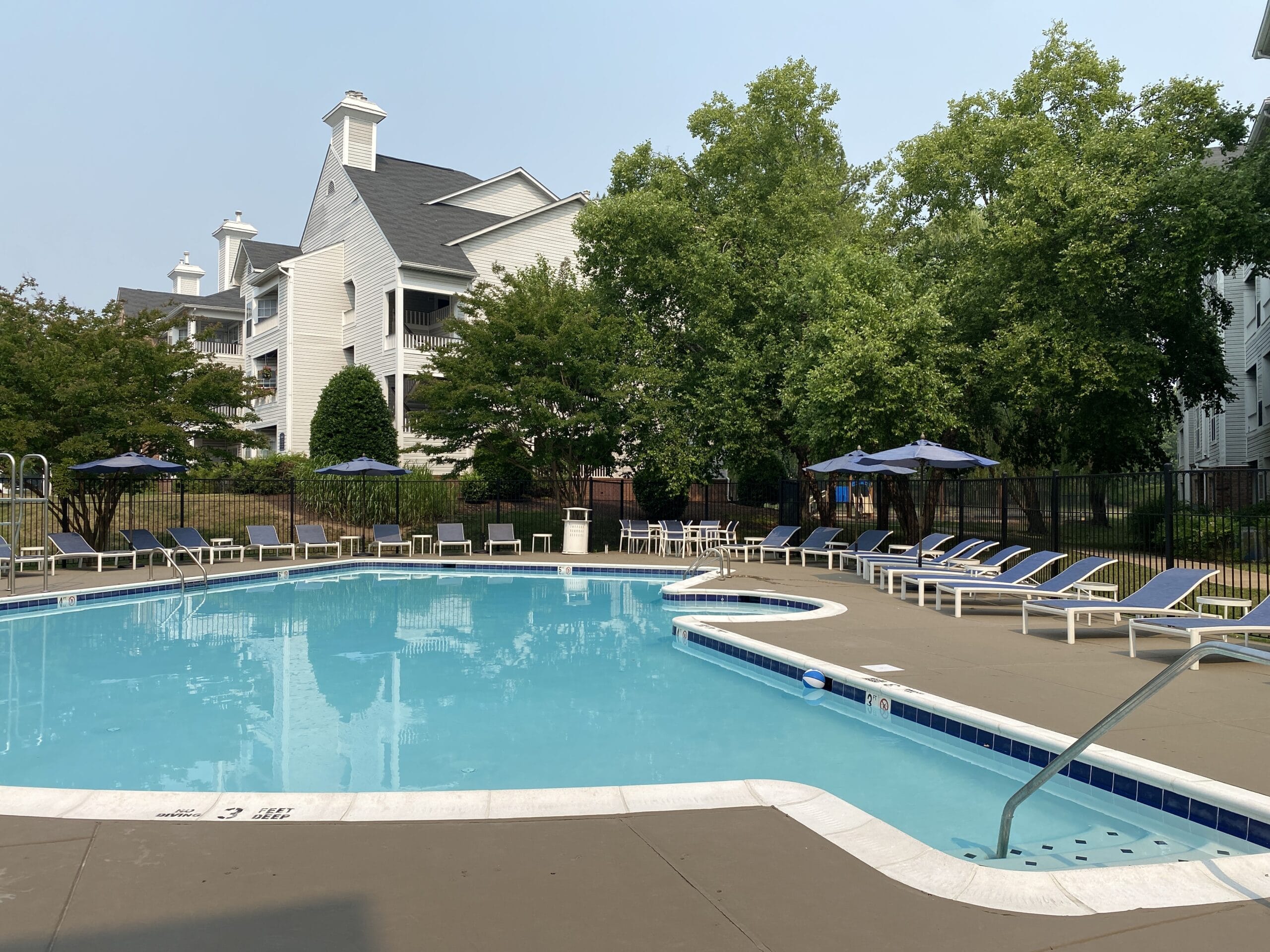 a swimming pool with chairs and a house in the background