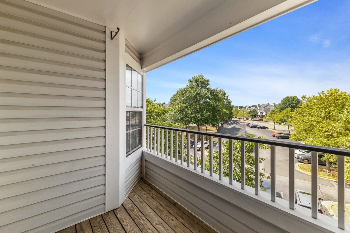 the view from the balcony of a home with white siding and wood flooring