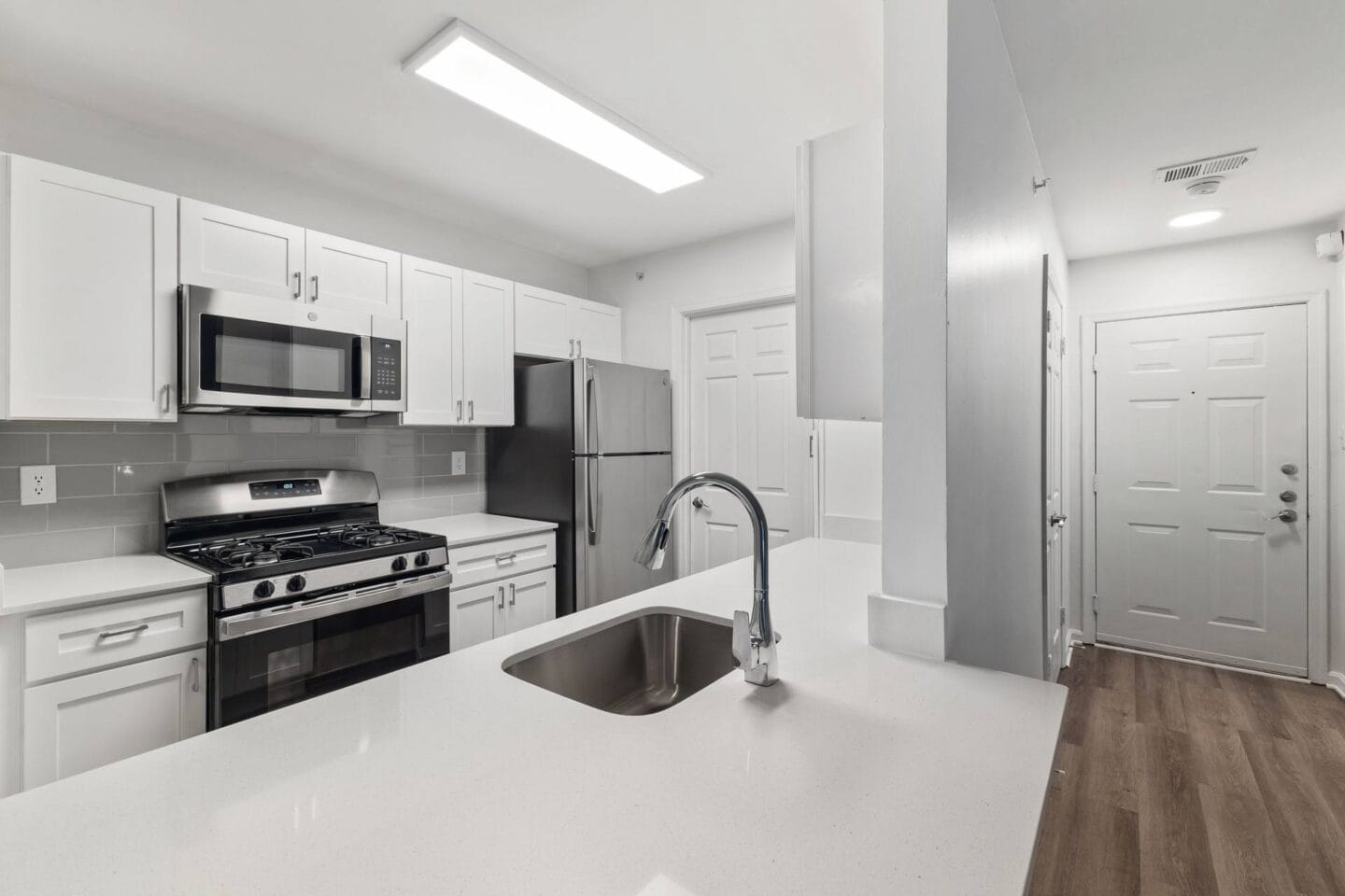 a white kitchen with stainless steel appliances and a sink