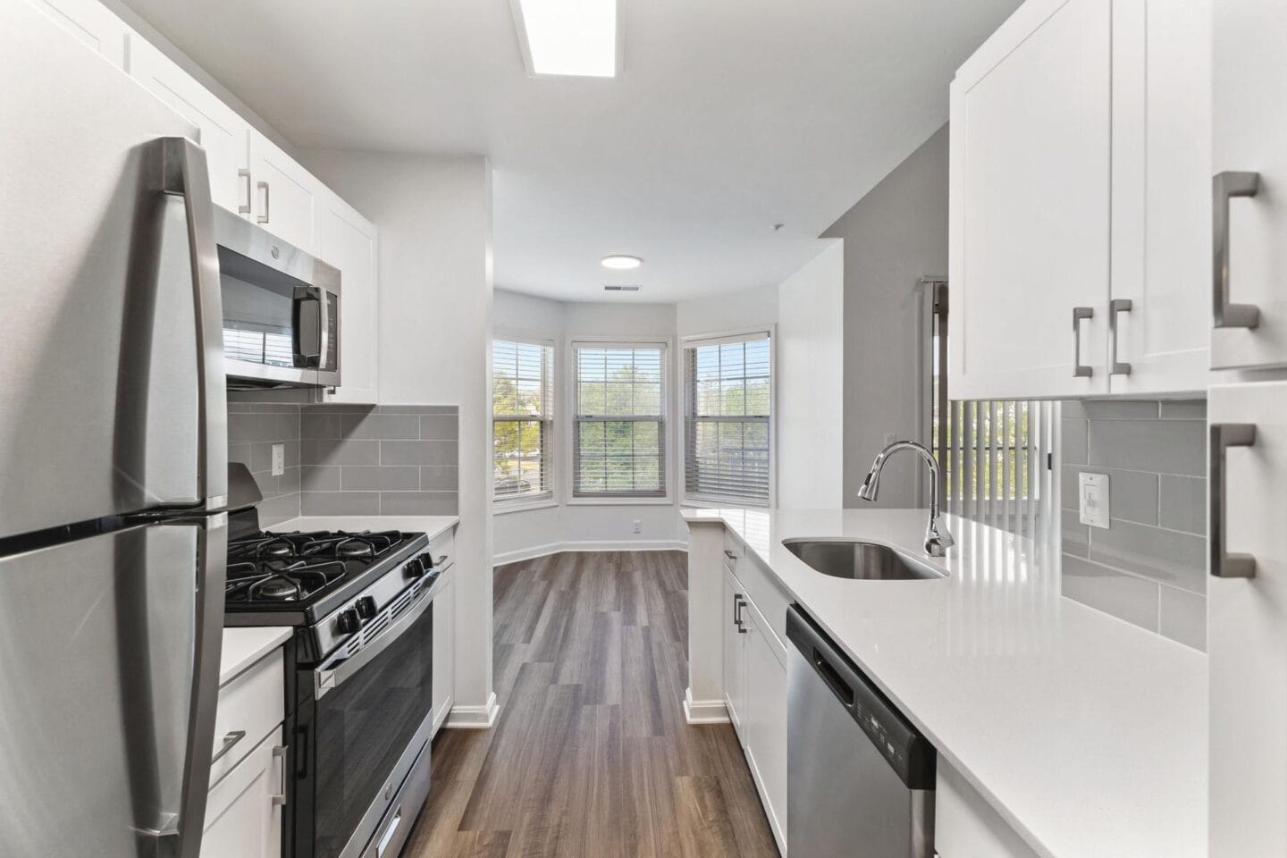 an empty kitchen with white cabinets and stainless steel appliances