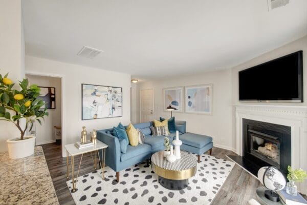 Living room with blue couches and a large tv above a fireplace at Windsor Kingstowne, VA 22315