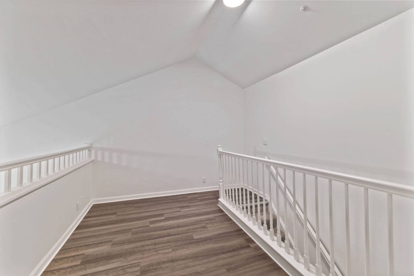 the upstairs landing of a home with white walls and a white staircase