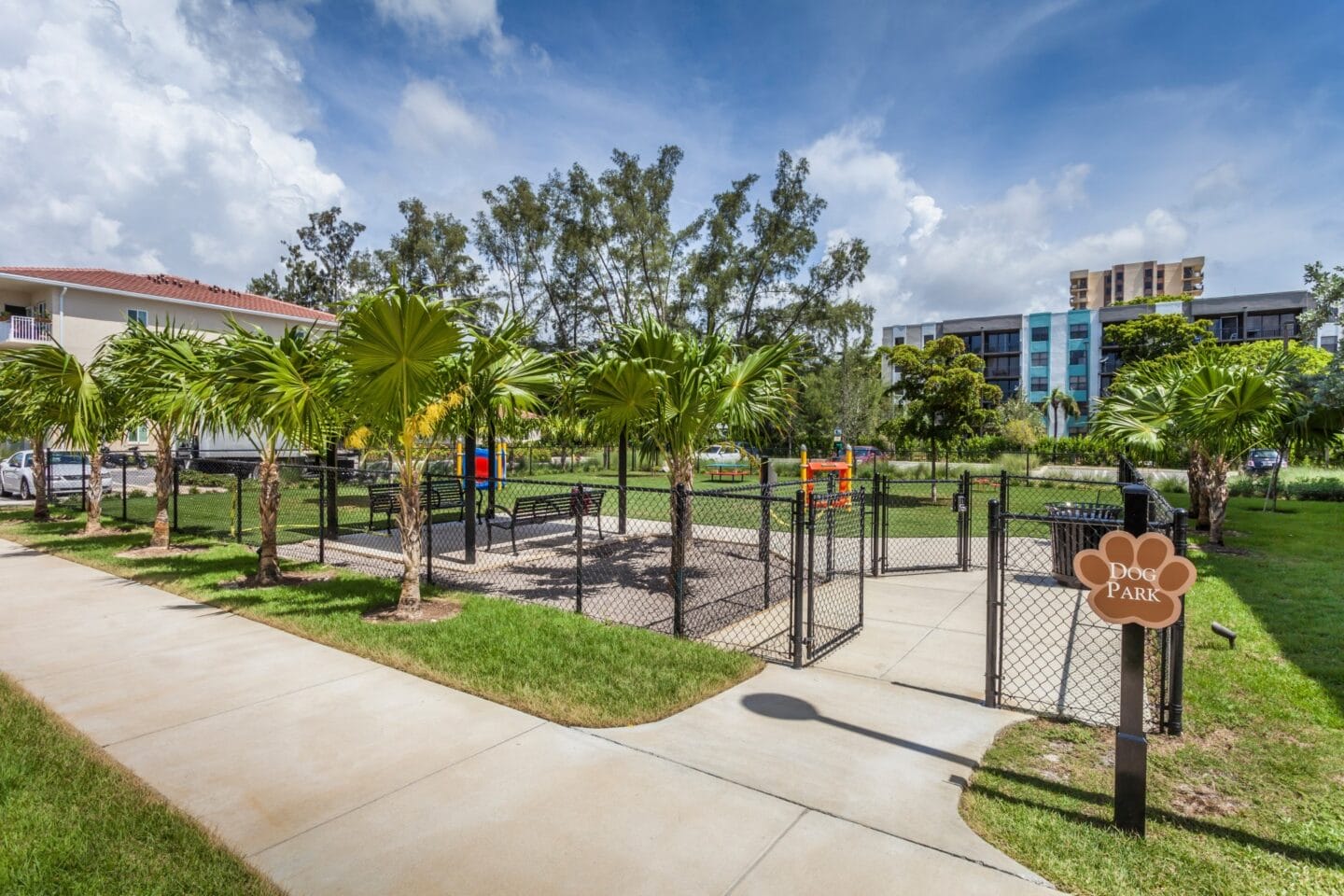 Fenced in dog park with palm trees and buildings at Windsor Biscayne shores in North Miami