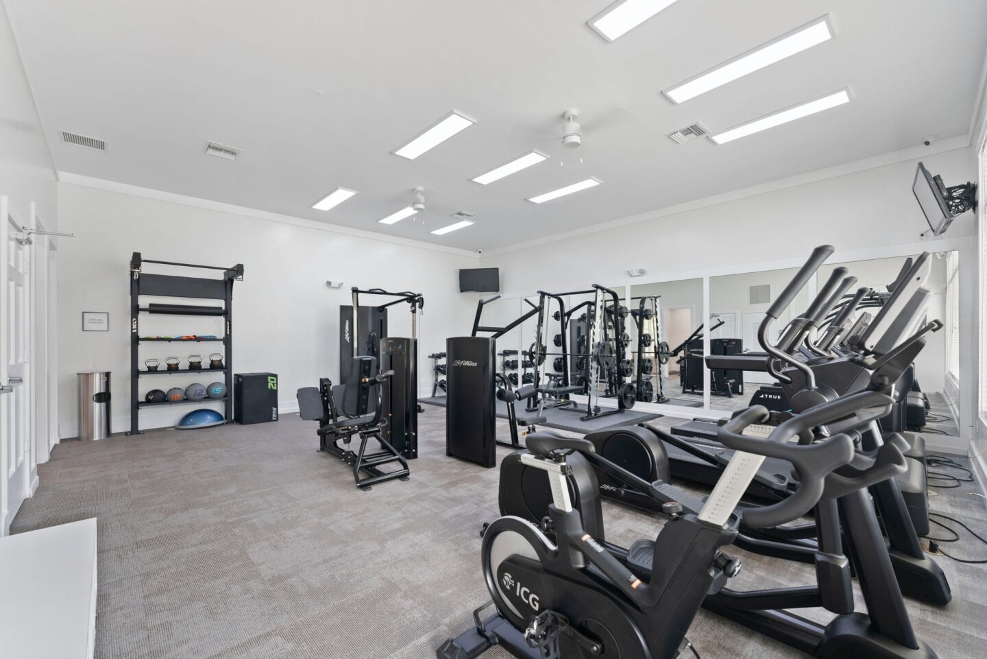 a gym with cardio equipment and weights on the floor