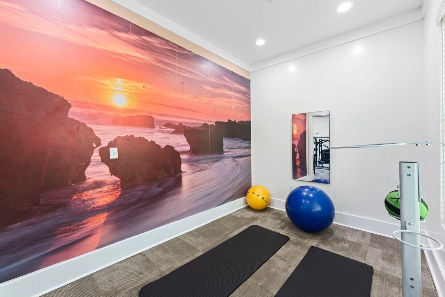 a workout room with yoga mats and a wall mural of the beach