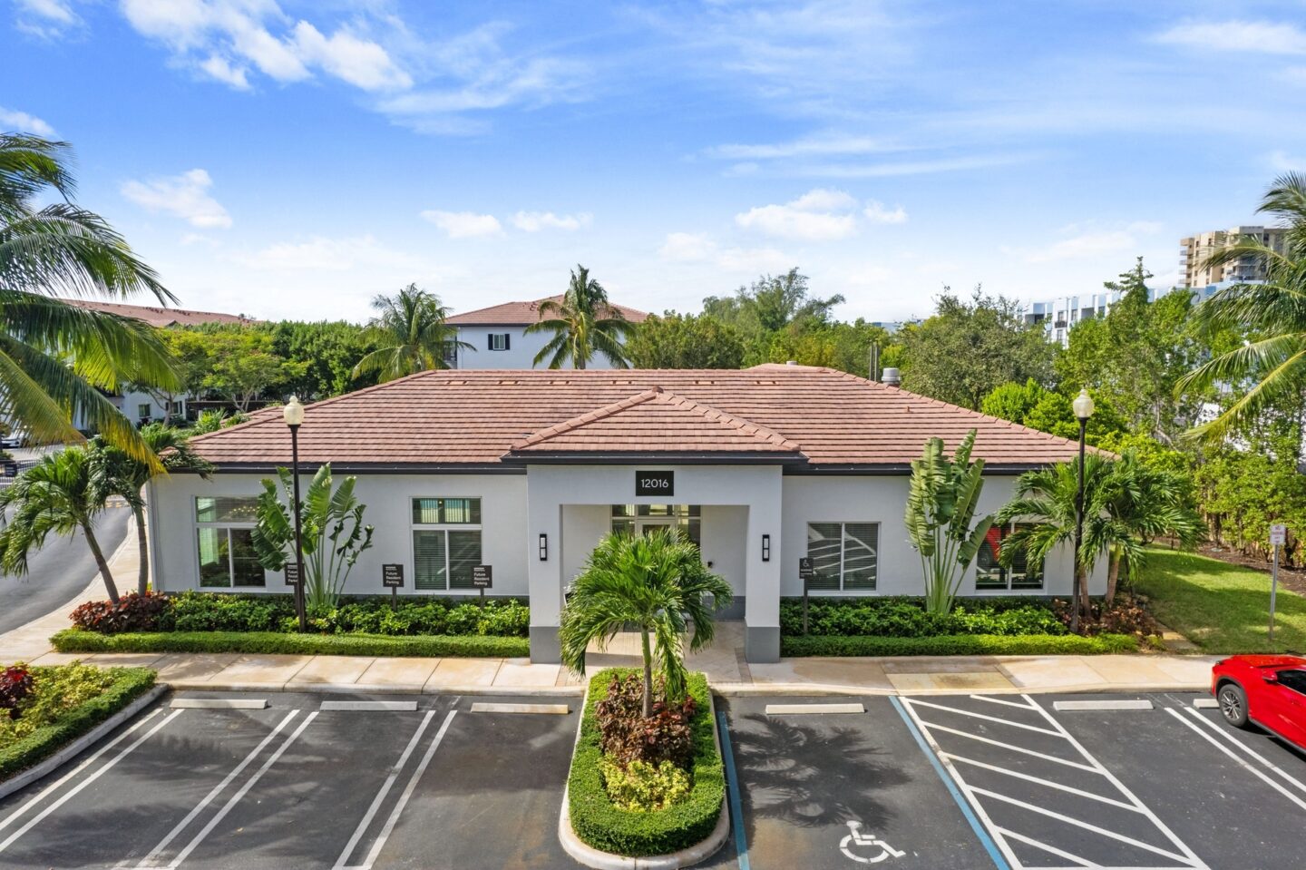 an empty parking lot in front of a house with palm trees