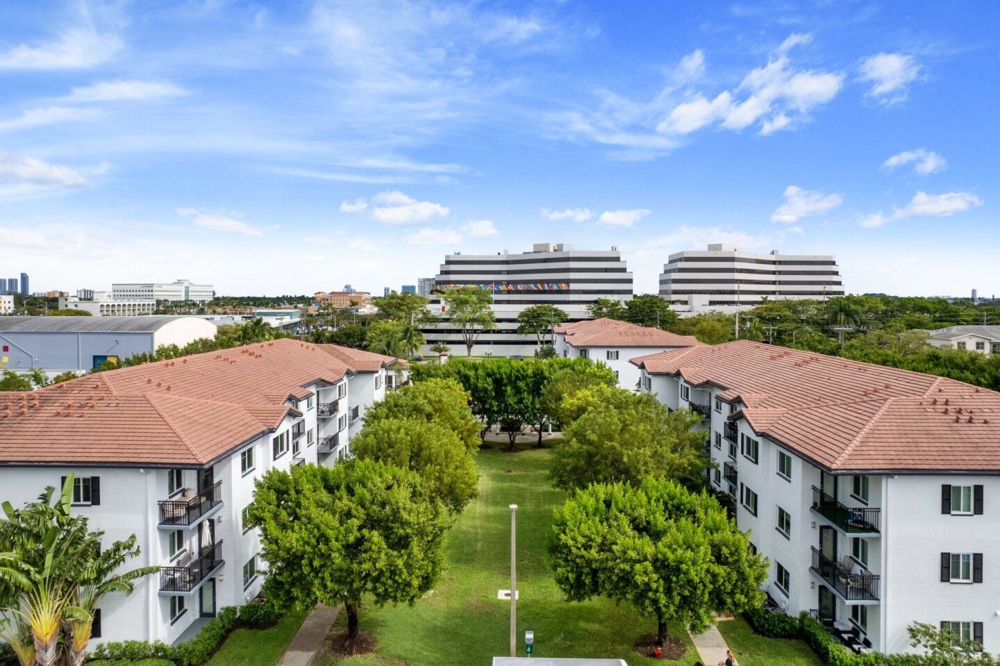 an aerial view of apartment buildings with a park and trees