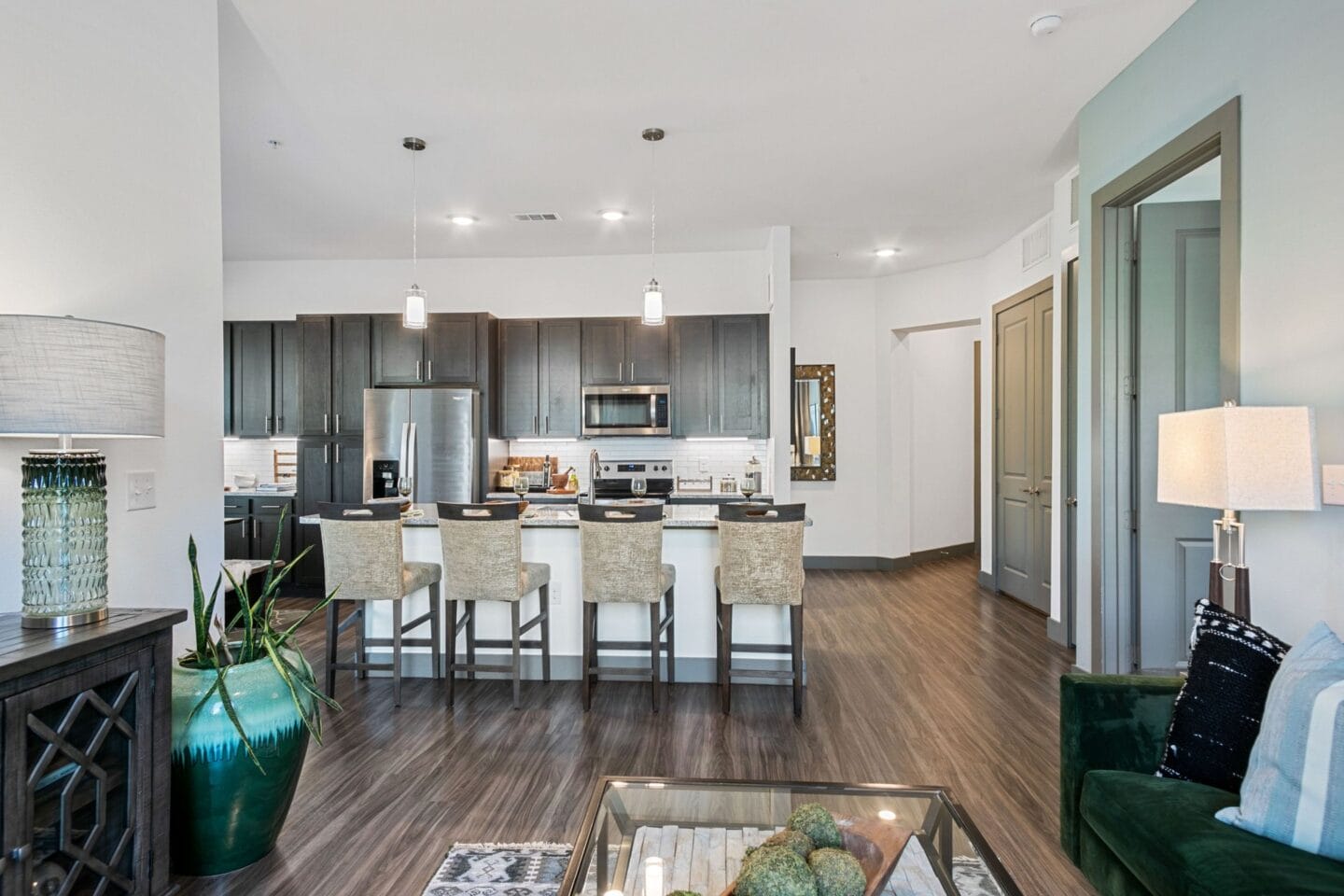 An open kitchen and living room with a large island and bar with stools at The Lakeyard District