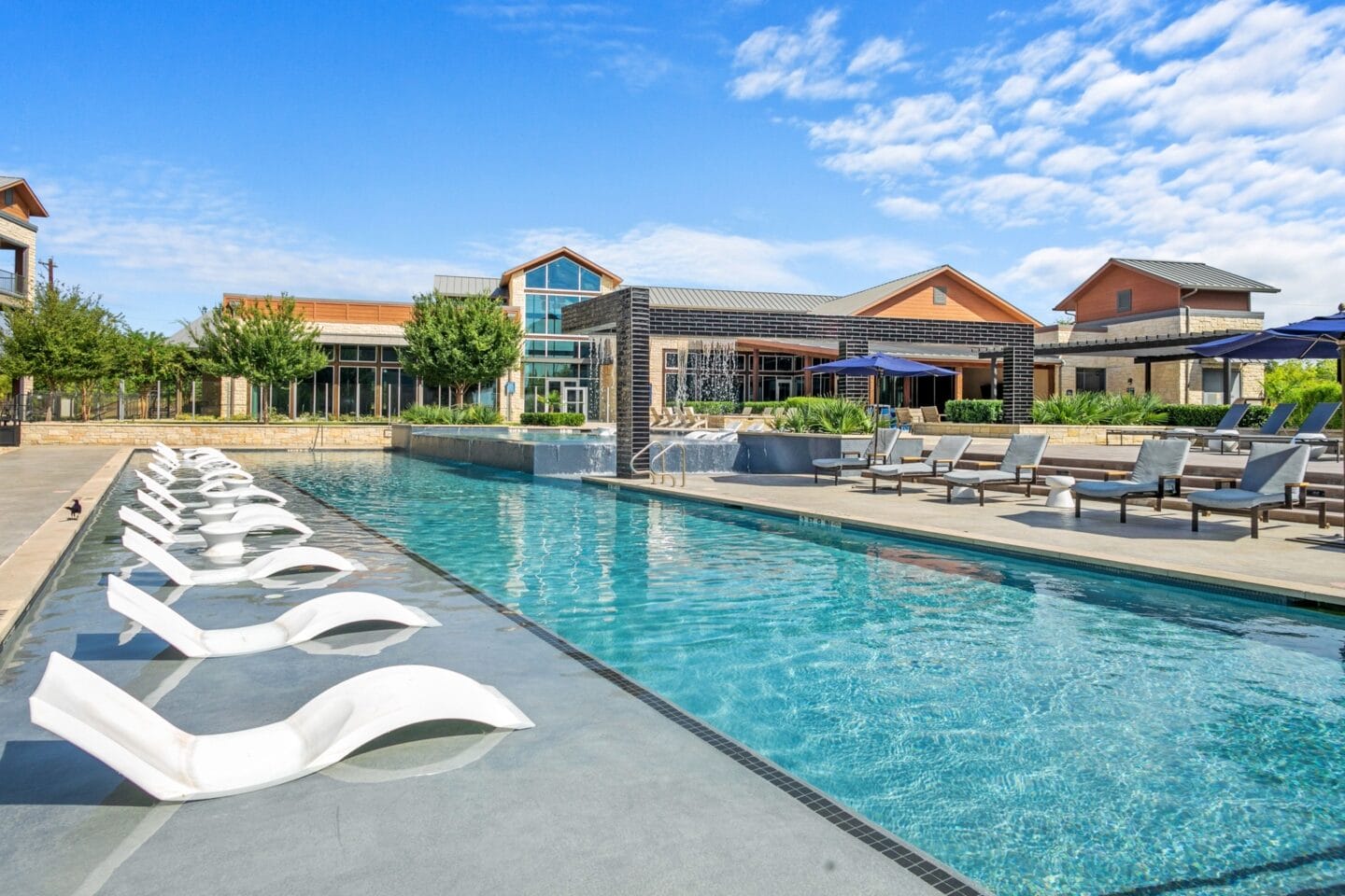 Pool with lounge chairs and a building in the background at The Lakeyard District