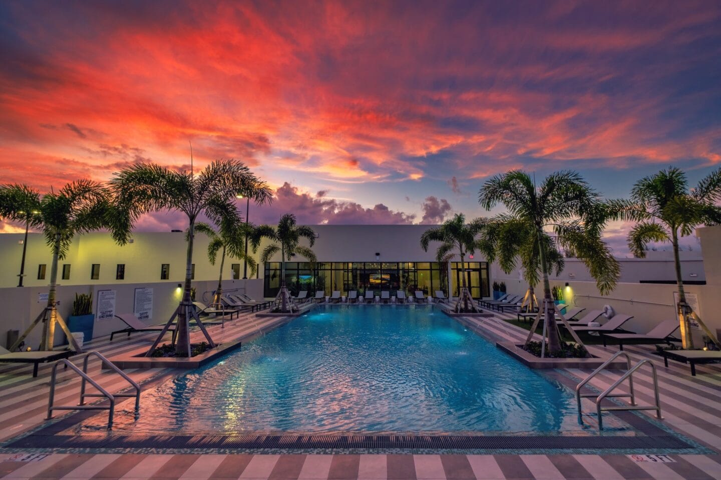 Pool with palm trees and a sunset in the background at Windsor Ludlam Trail in Miami, FL.