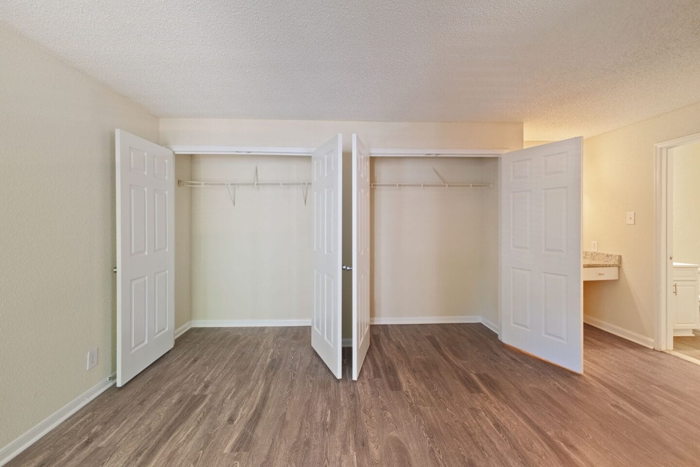 the spacious living room of an apartment with white doors and wood flooring