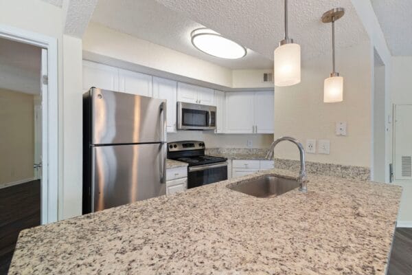 a kitchen with a granite counter top and a stainless steel refrigerator