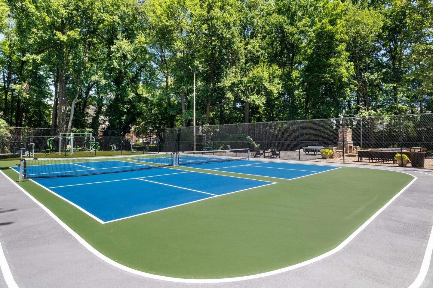 a tennis court with benches and trees in the background